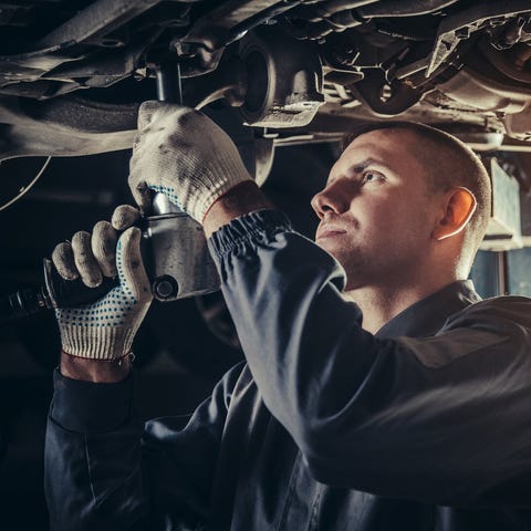 A mechanic repairs a car in an auto repair shop.