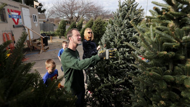 Chris and Sara Birn of Appleton look for a Christmas tree with their sons Nick and Ben on Friday at the YMCA Christmas tree lot in the parking lot of Festival Foods on Northland Avenue in Appleton.