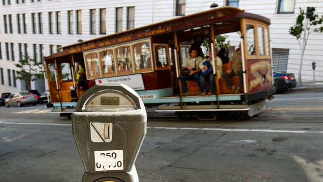 In this Oct. 27, 2009 file photo, a cable car passes a parking meter near San Francisco's financial district. San Francisco City Attorney Dennis Herrera on Monday, June 23, 2014 issued a cease-and-desist demand to a mobile app called Monkey Parking, which allows people to auction off public parking spaces that they're using to other nearby drivers.