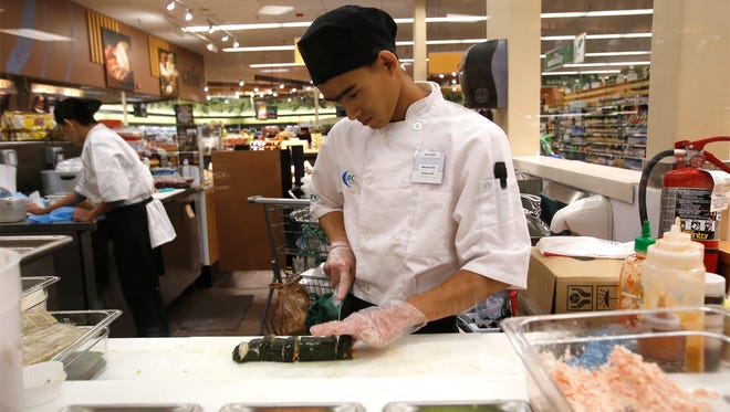 Sushi chef Maung Hein cuts sushi rolls Friday at Smith's Food and Drug in Farmington.
