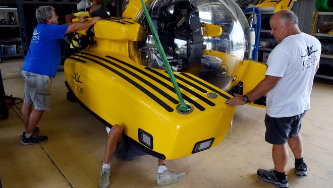 Triton Submarine LLC employees Tim Kutsin (from left), Colin Quigley and Kelvin Magee attach one of two main ballast tanks on a three-person submarine, Wednesday, Aug. 2, 2017, at the shop in Vero Beach. Triton was formed in 2008 and has completed 14 submersibles over the last nine years.