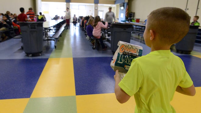 A student walks through the cafeteria Thursday during lunch at Grosuch West Elementary School in Lancaster. Brad Hutchinson, owner of Company Wrench in Carroll, paid more than $13,000 to clear student's school lunch debts in four districts throughout the county.