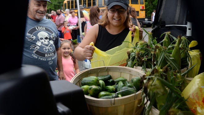 Jessie Velez-Torres (right), her niece Jaylyn Cortes, 4, and her father, Cortes' grandfather, Reinaldo Velez, all of Vineland, load up produce they bought at the produce auction at Vineland's Jersey Fresh Festival on Sunday at Giampietro Park in Vineland.