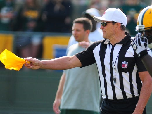NFL official Ed Hochuli waves a penalty flag during drills at Green Bay Packers training camp practice at Ray Nitschke Field, Thursday, July 31, 2014.