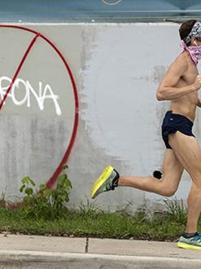 Christopher Matos wears a bandana over his face while running on East 7th Street on Monday April 6, 2020, during the coronavirus pandemic. Austin and Travis County are recommending the use of fabric face coverings when away from home to slow the spread of the coronavirus.