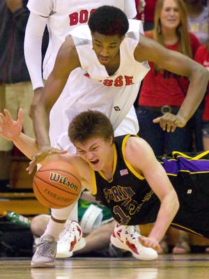 Guerin Catholic High School's Adam Hufford dives for the ball as Evansville Bosse High School sophomore JaQuan Lyle moves in to pick it up. Guerin Catholic defeated Bosse 75-56 to advance to the State Championship game. Guerin Catholic High School faced Evansville Bosse High School in IHSAA Semi-State 3A Boys Basketball action Saturday, March 17, 2012, at Seymour High School. Doug McSchooler/for The Star