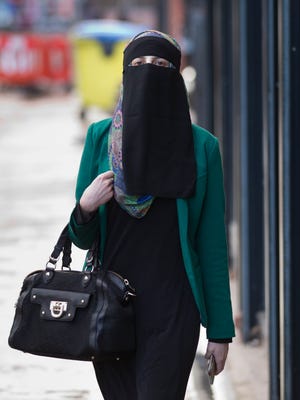 A woman wearing a full face veil walks in Blackburn, England, Wednesday, Sept. 19, 2013.