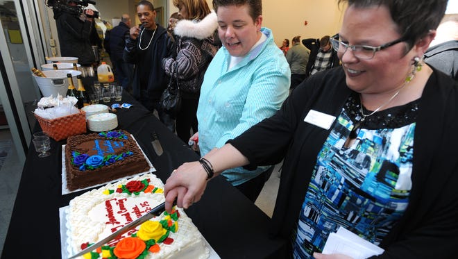 Sheri Folta, left, and her wife, Cassandra Varner, slice one of two anniversary cakes together last month in Ferndale, Mich.