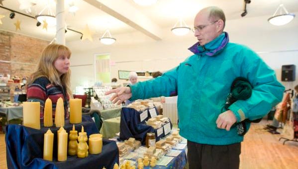 Kathy Kohlman, leftl of Cohoctah Honey Works talks with customer Darren Quigley of Howell about her wax candles at the 2009 Winter Marketplace at The Opera House in Howell.