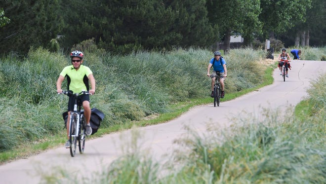 People bike toward a Bike to Work Day station on the Power Trail in 2015. Developer Byron Collins has donated 5 acres adjacent to the trail to the city of Fort Collins.