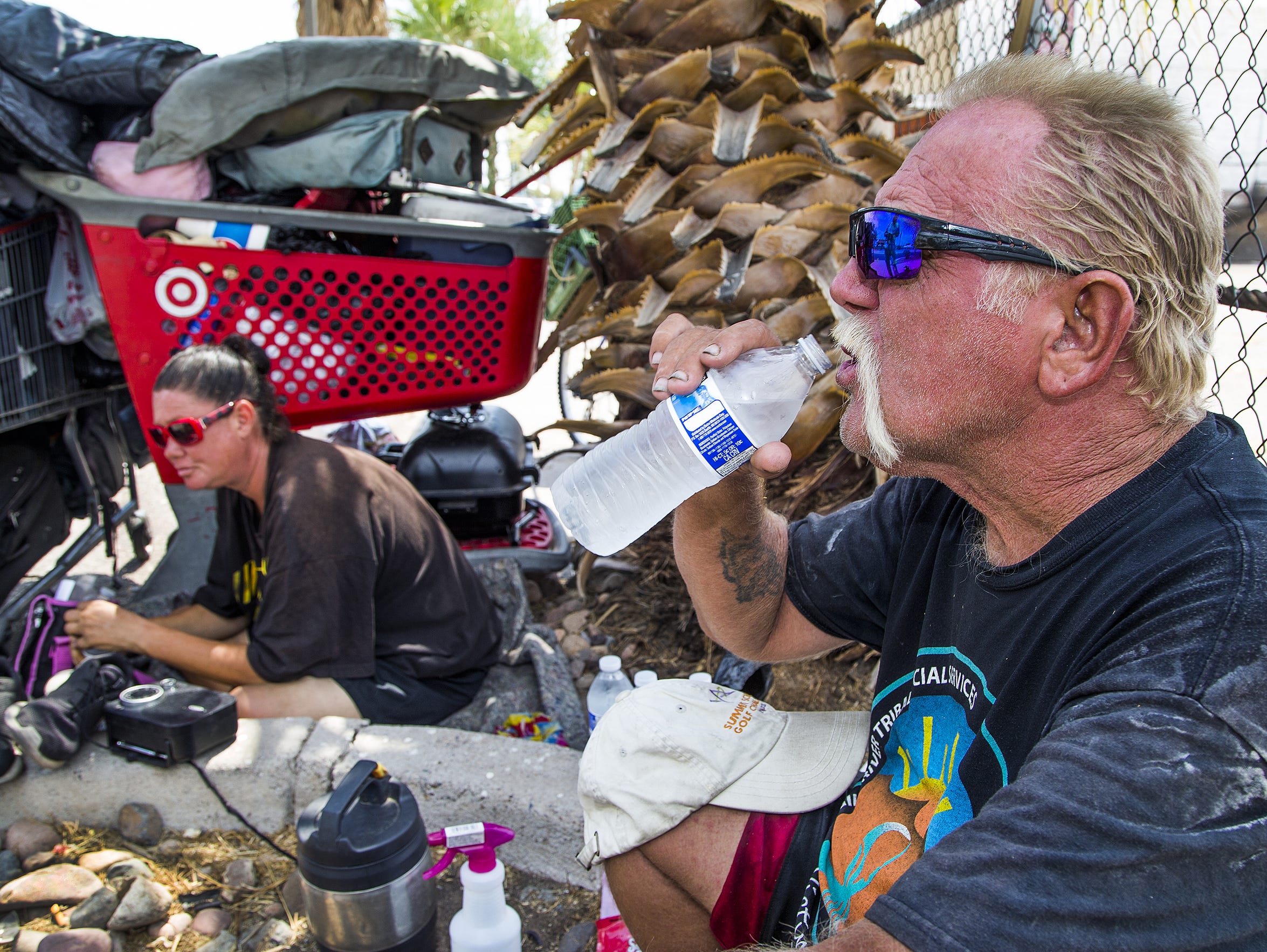 Whitey Hurst, 50, right, takes a swig from a cold bottle