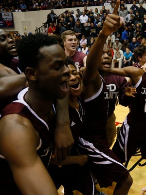 U-D Jesuit's Cassius Winston, right with his finger up, celebrates with his teammates after he made the game winning shot as time ran out for their game 56-54 win over Clarkston in their boys basketball Class A quarterfinals at Calihan Hall on Tuesday, March 24, 2015 in Detroit.