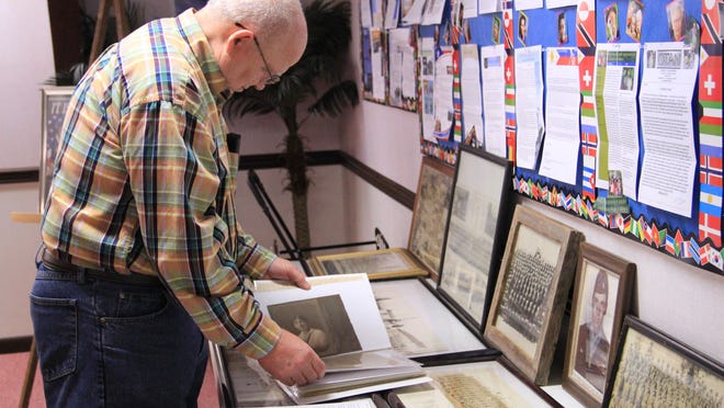 L.V. Rhodes thumbs through an album of photos taken of veterans during World War II. The scrapbook is part of a collection memorabilia he brings out during patriotic holidays like Memorial Day to display at Hope Baptist Church in Alexandria.