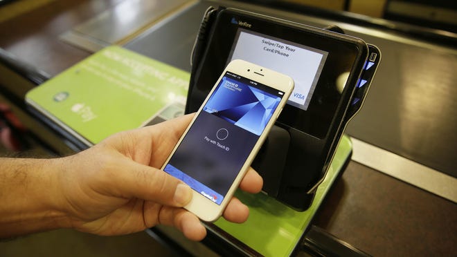 Eddy Cue, Apple senior vice president of Internet software and services, demonstrates the new Apple Pay mobile payment system at a Whole Foods store in Cupertino, California.