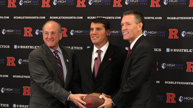 Rutgers University President Robert Barchi (left) and Athletic Director Patrick Hobbs (right) flank Chris Ash, head coach of the Rutgers University Scarlet Knights football program, during a news conference in the Hale Center. The school subsidy required for Rutgers athletics has dropped by nearly 50 percent in two years.
