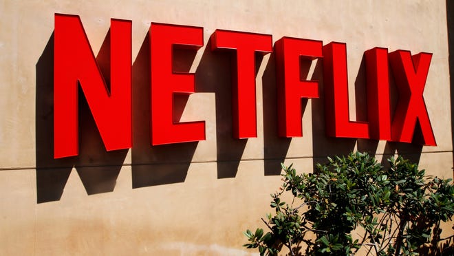 A red Netflix logo in the form of a sign on a beige stucco wall.