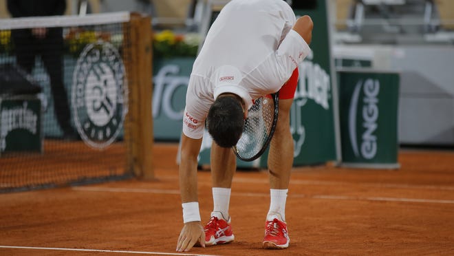 Novak Djokovic touches the clay court after winning his match against Mikael Ymer at the Roland Garros stadium in Paris on Tuesday.