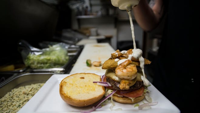 Assistant kitchen manager Taylor Randall applies the finishing sauce onto a Surf ‘n Turf burger on Tuesday, March 6, 2018, at Stuft - A Burger Bar in Old Town Fort Collins, Colo.