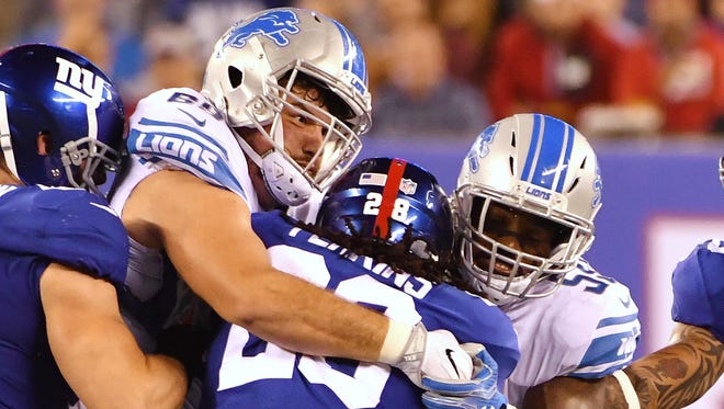 Lions defensive linemen Anthony Zettel, left, and Tahir Whitehead stop Giants running back Paul Perkins on Monday night.