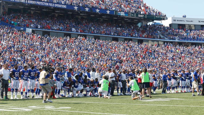 Camera operators and photographers cover Buffalo Bills players kneeling in protest during the national anthem before a game against the Denver Broncos at New Era Field.