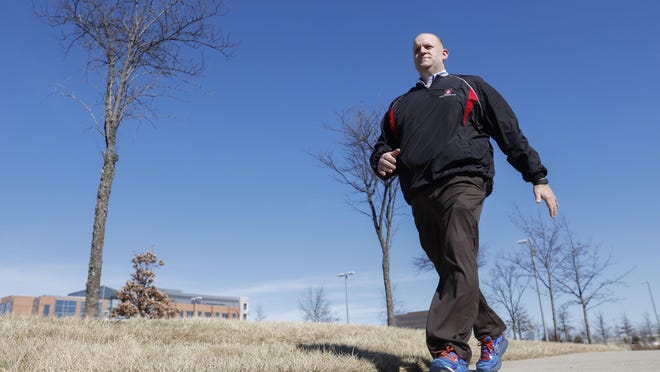 Brett Broviak, of Indiana University Health, walks with his Fitbit fitness tracker in Carmel, Ind. Fitbit works with employers to subsidize fitness trackers for their staff.