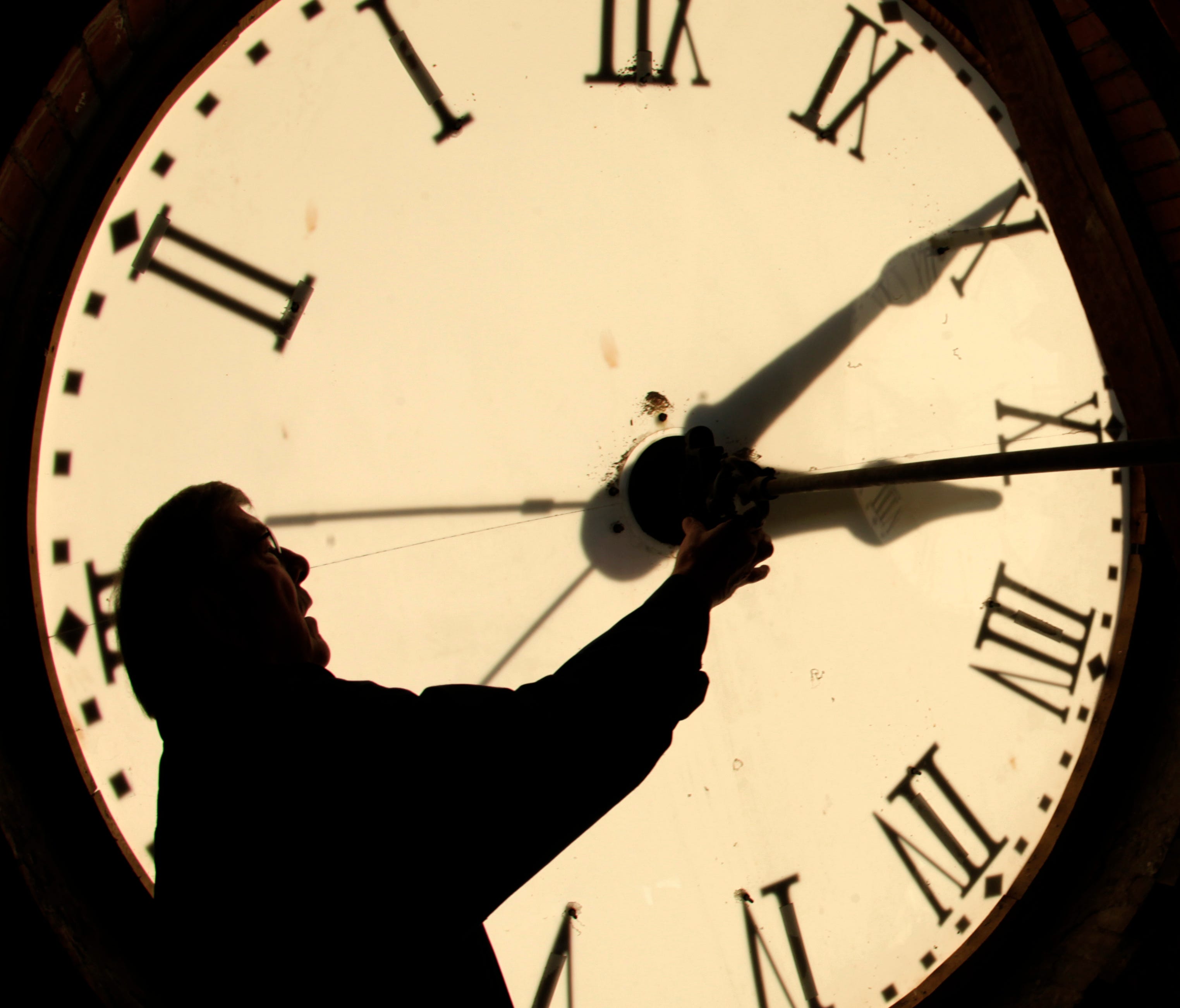 Custodian Ray Keen checks the time on a clock face Nov. 6, 2010, in Clay Center, Kan. Arizonans say to heck with that and keep their clocks on Mountain Standard Time all year.