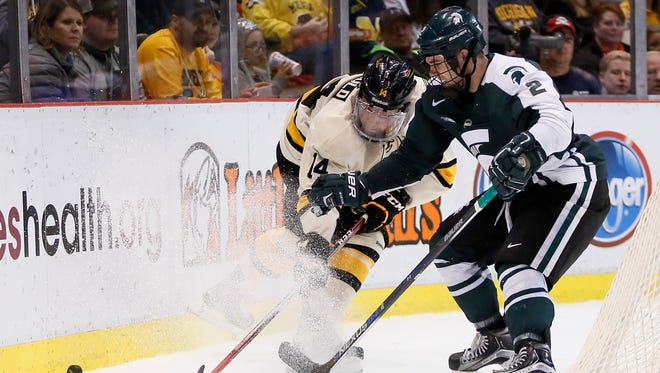 Michigan State's Zach Osburn, right, fights for to the puck against Michigan Tech on Dec. 29, 2015, in Detroit.