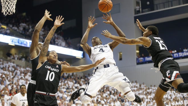 Xavier Musketeers guard Edmond Sumner (4), center, loses the ball on the way to the basket as Cincinnati Bearcats guard Troy Caupain (10), left, and Cincinnati Bearcats guard Kevin Johnson (25) defends in the second half during the 83rd annual Crosstown Shootout NCAA basketball game between the Cincinnati Bearcats and the Xavier Musketeers, Saturday, Dec. 12, 2015, Cintas Center in Cincinnati.