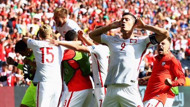 Robert Lewandowski and Poland players celebrate their win in front of the Switzerland supporters.