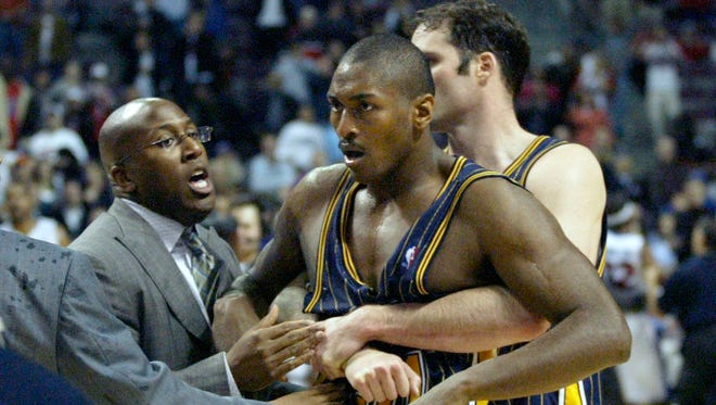 Ron Artest is restrained by Austin Croshere before being escorted off the court following their fight with the Pistons and fans on Nov. 19, 2004, in Auburn Hills, Mich.