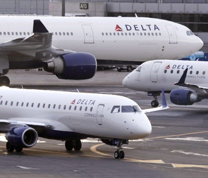 A Delta Connection Embraer 175 aircraft, foreground, taxis to a gate at Logan International Airport in Boston on Jan. 8, 2018.