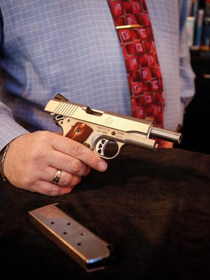 Matt DePhillips, manager of The Pawn Shop, holds a Ruger handgun on Friday, Jan. 26, 2018.