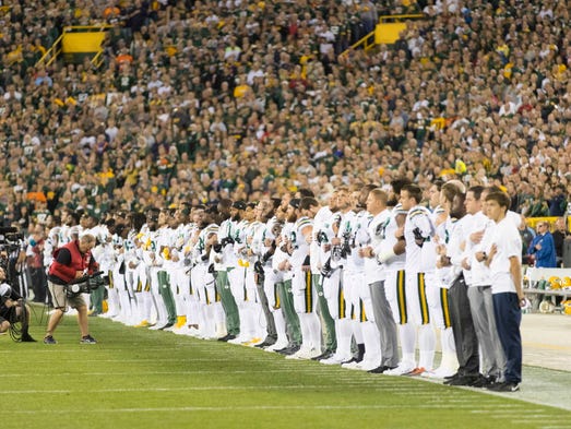 The Green Bay Packers link arms during the national