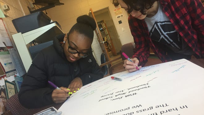 Vineland High School Poetry Slam students created a collaborative poem to offer hope to survivors of the Parkland, Fla. mass shooting. Jordan Martinez, (left) and Jonathan Lopez add their signatures to the work.