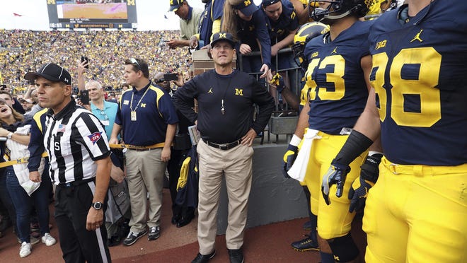 FILE - In this Oct. 1, 2016, file photo, Michigan coach Jim Harbaugh, center, waits to take the field with his players before an NCAA college football game against Wisconsin at Michigan Stadium in Ann Arbor, Mich. Michigan faces Maryland on Saturday. (AP Photo/Tony Ding, File)