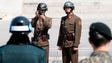 A North Korean soldier takes a photograph while two