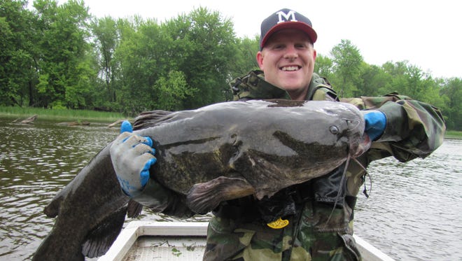 Kyle Hoffman, a volunteer assisting a Department of Natural Resources fisheries crew, holds a flathead catfish caught during a survey on the Wolf River.