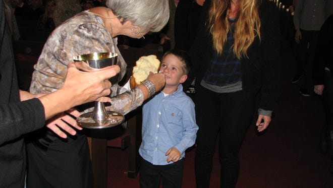 The Rev. Lori Lampert offers bread to a young member of the Downtown Church during Holy Communion.