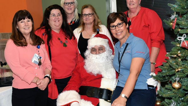 The St. Lucie Medical Center employees prepared Christmas items for the families of Helping People Succeed, a nonprofit organization working with Helping People Succeed fifteen families. The staff members are, from left: Teresa Emmons, Heidi White, Karen Giovengo, Tami Speed, Santa (Andy Aiello), Maggie Stewart, Jan Meier