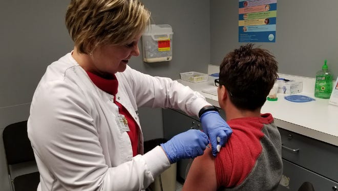 Public Health Nurse Jane Moylet give Jennifer Michael a flu shot at the Sandusky County Health Department.