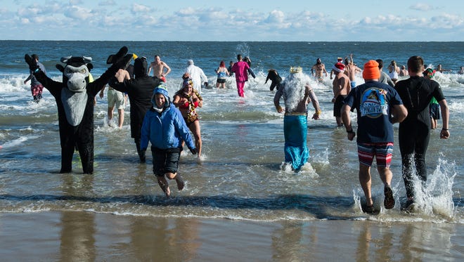 Swimmers emerge from the ocean during the 24th Annual Penguin Swim near the Princess Royale Hotel in Ocean City on Monday, Jan. 1, 2018. 