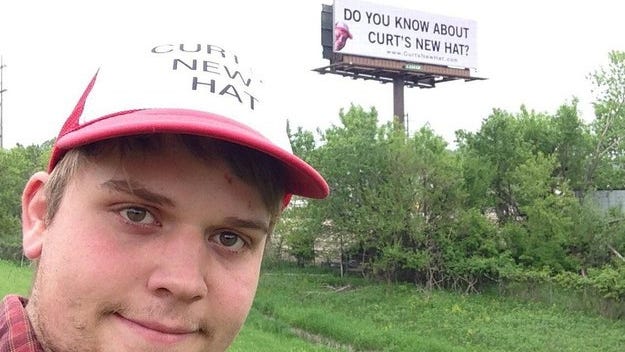 Curt Oren stands near the billboard he rented in Cedar Rapids for Curt’s New Hat.