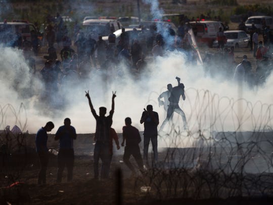 Palestinians protesters run from tear gas fired by Israeli troops in Israel Gaza border, Friday, June 8, 2018.