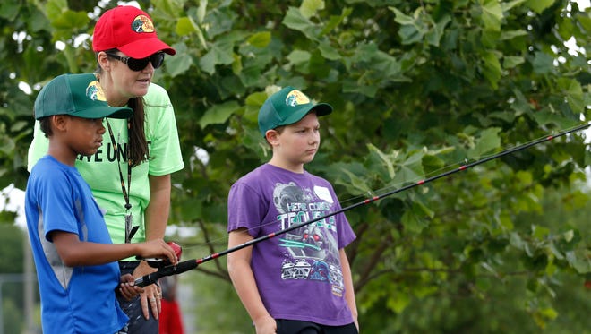 KamRay Rutledge, 8, reels in his line with United Way Day of Caring volunteer April Brown instructing him at a pond at the Bass Pro Shops corporate headquarters on Kearney Street on Thursday, June 22, 2017.