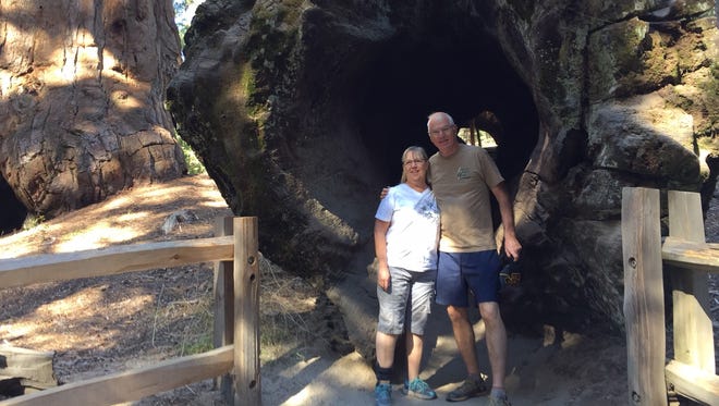 Norris Burkes and his wife, Becky, at the marriage retreat standing before a fallen sequoia big enough to walk through.