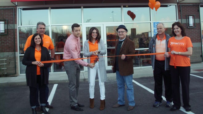 Orangetheory Fitness, a national fitness franchise, opened Thursday in the Newport Pavilion shopping center. Owners Chase and Stephanie Whitehead (center) pose for a photo during the ribbon-cutting ceremony.