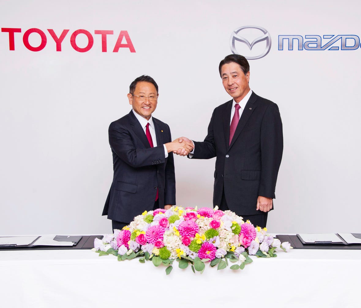 Toyota CEO Akio Toyoda and Mazda CEO Masamichi Kogai celebrate a partnership between their companies to develop electric vehicles and self-driving cars and build a $1.6 billion U.S. plant.