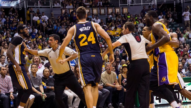 A referee separates Utah Jazz forward Trevor Booker (33), left, and Los Angeles Lakers center Roy Hibbert (17), far right, after an altercation between the players during the second half of an NBA preseason basketball game, Oct. 6, 2015, in Honolulu.