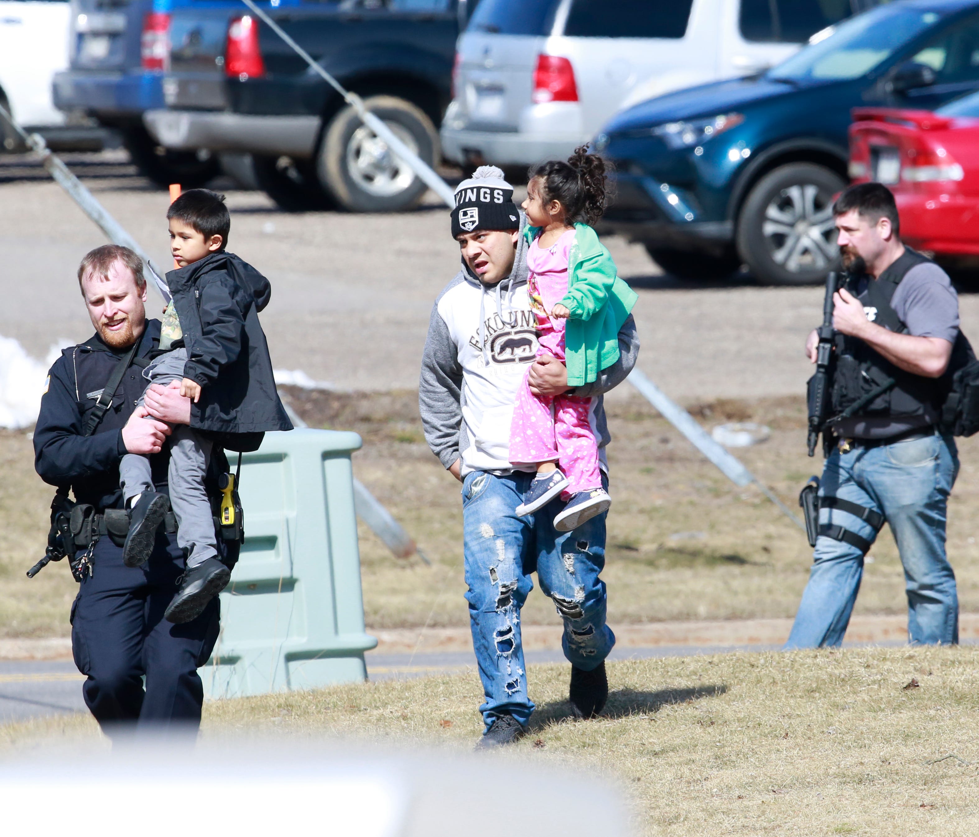 Police officers escort a family from the apartment complex to safety Wednesday on the corner of Aspen Street and Ross Avenue in Weston.