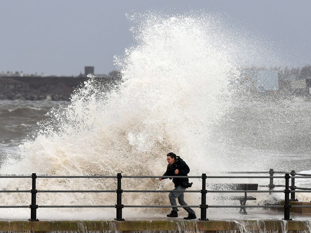 A man is hit by a wave at New Brighton in northwest England on Nov. 16, 2016, as he runs along the seawall.